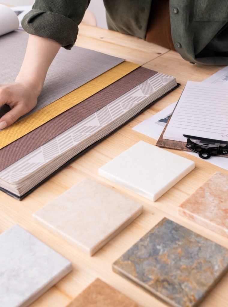 Hands of female interior designer with pencil over paper making notes about color, pattern and texture of wallpapers for new client